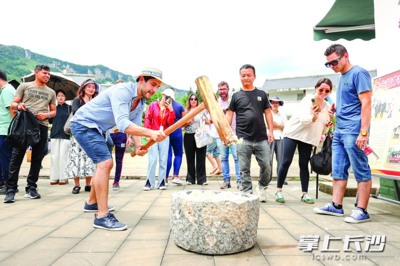 外国游客在化屋村体验苗族打糍粑。 均为毕节日报供图